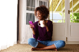 Woman holding coffee cup and smiling while looking at phone
