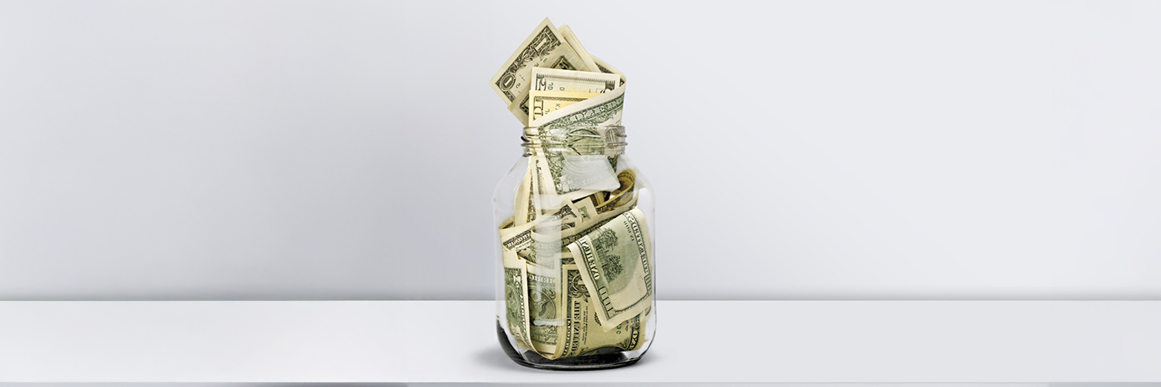 Image of mason jar filled with 100$ bills