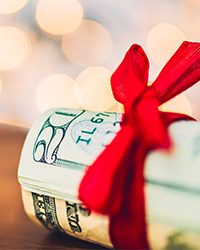 Image of a roll of twenty-dollar bills wrapped in a red bow.